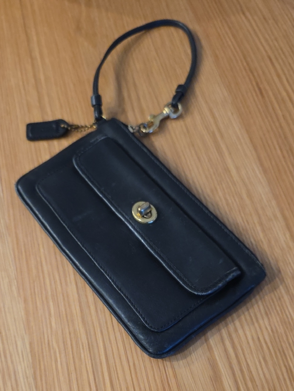vintage Coach black leather front flap wristlet with a turn lock closure. [1, 2]